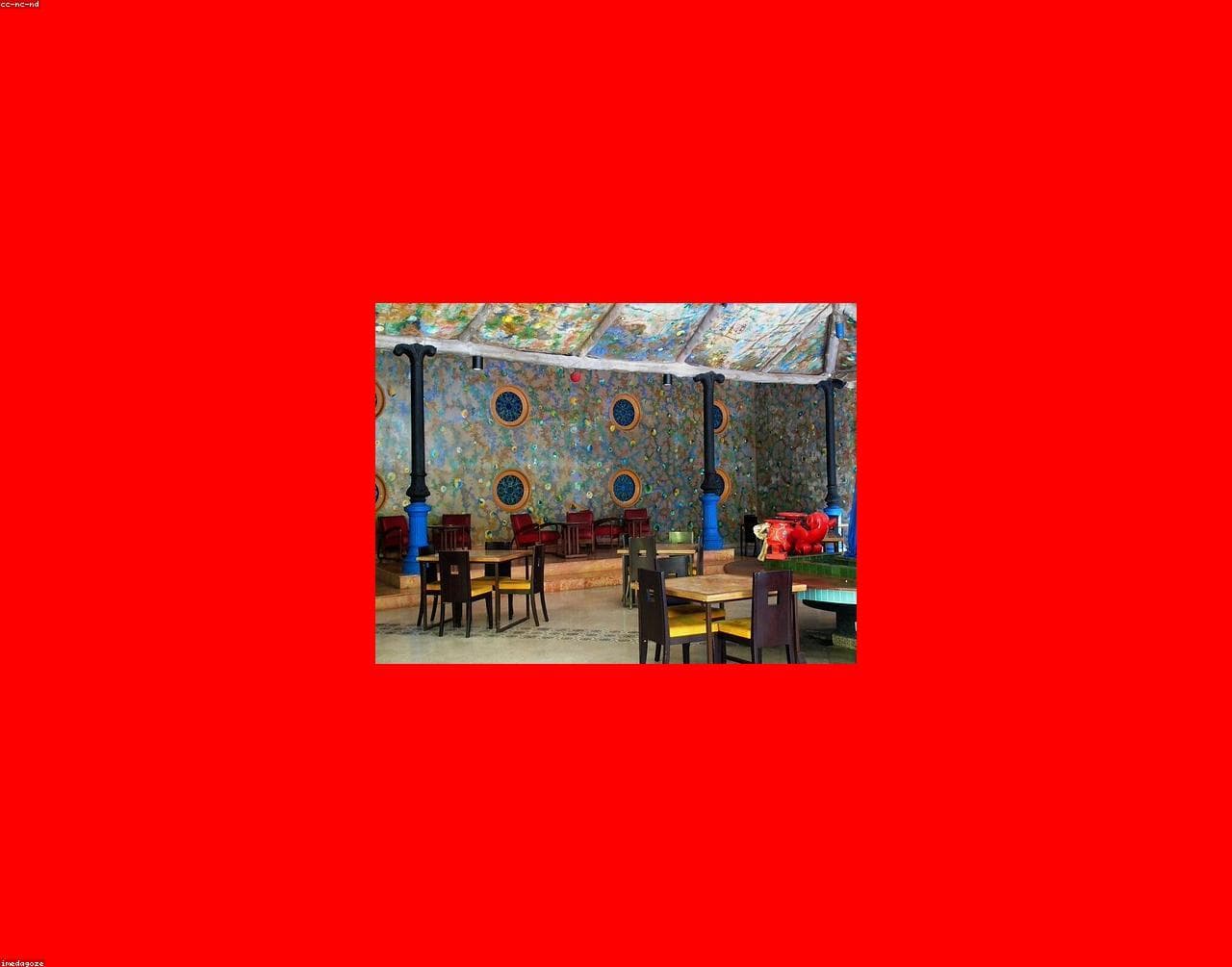 Warm, colorful dining room with orange walls and a "Good Vibes Only" neon sign